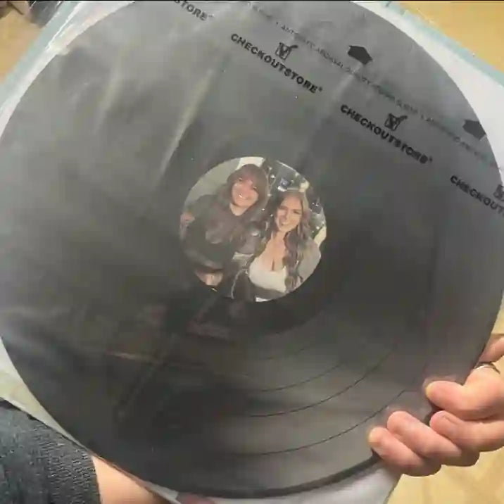 A professional one-off custom vinyl record in a protective sleeve, featuring a bespoke photo label of two friends.